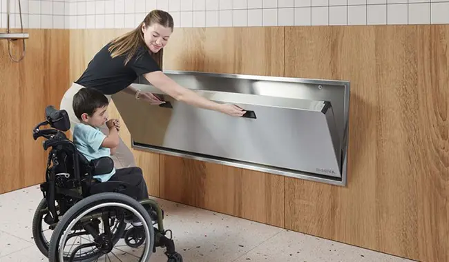 woman helping child into a changing station