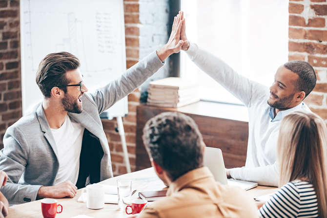 Professionals high-fiving around a conference table