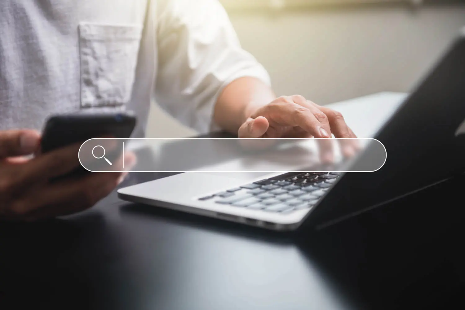 search bar super imposed over person on laptop holding phone