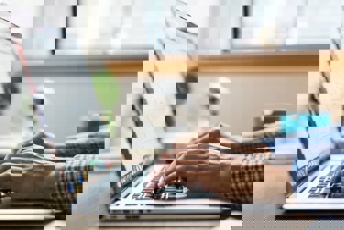 A man using a laptop to come up with a digital marketing budget breakdown.