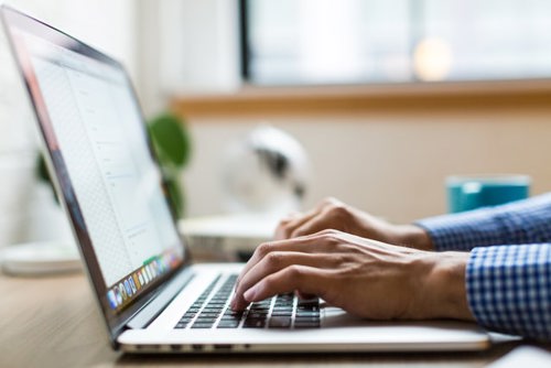 A man using a laptop to come up with a digital marketing budget breakdown.