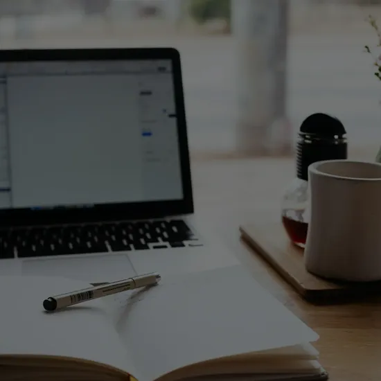 laptop coffee mug and notepad on a desk