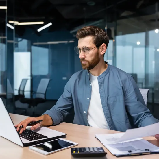 person with glasses looking at a laptop